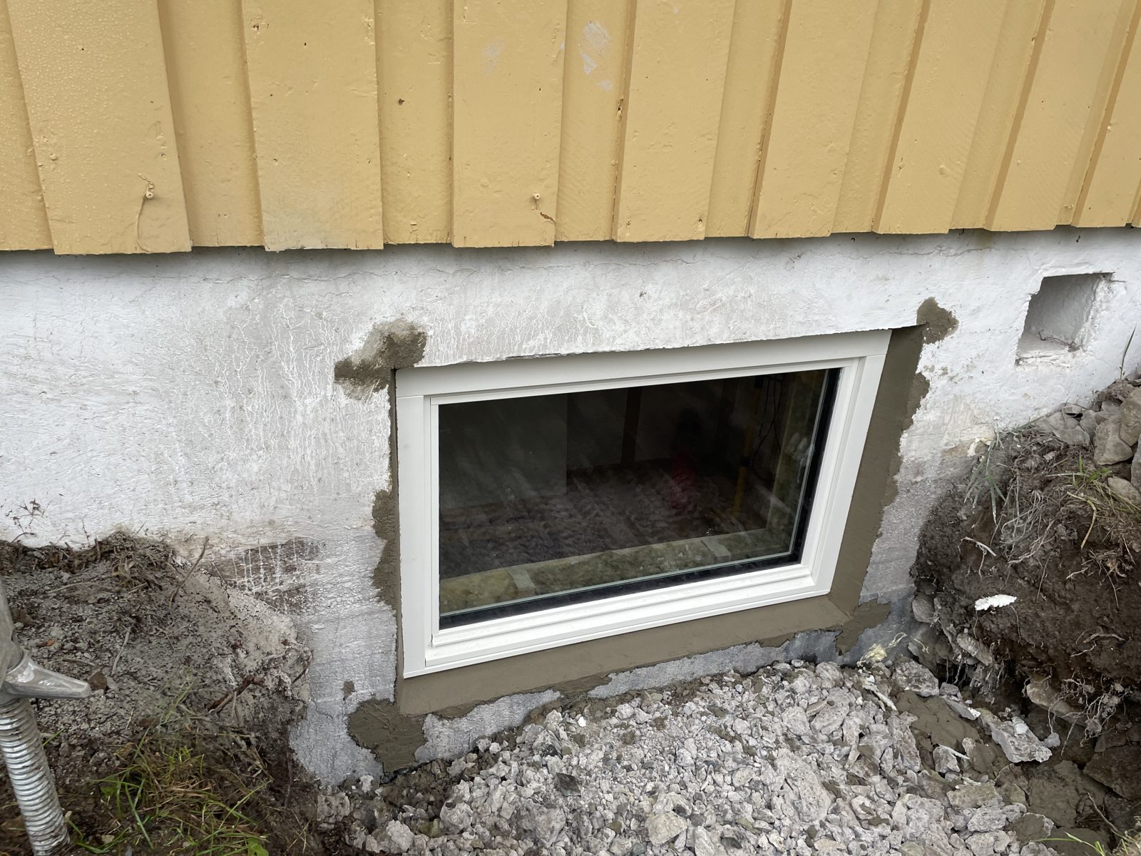 Ferdig innsatt kjellervindu i saget åpning, pusset og tettet mot grunnmuren