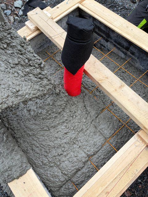 Betongen fylt rundt trekkrøret — fundamentet avrettes for montering av ladestolpe